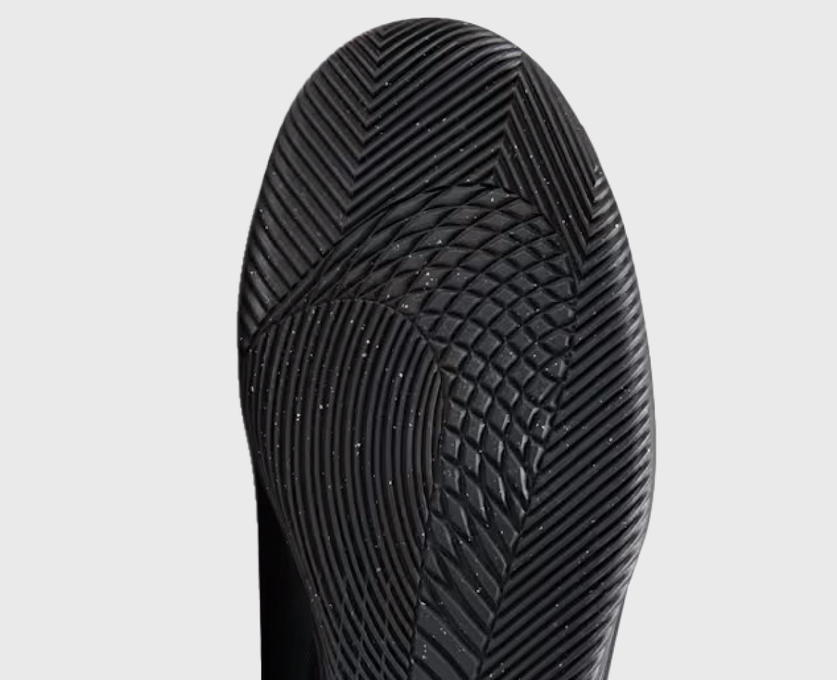 Indoor outsole viewed from below — a flat gum rubber sole providing grip on hard court surfaces